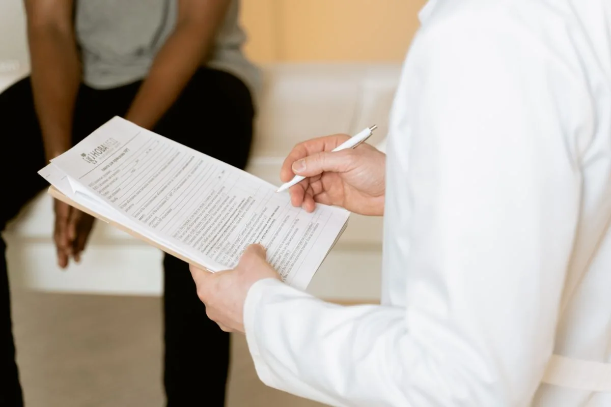 Profesional sanitario tomando notas durante una consulta con una paciente